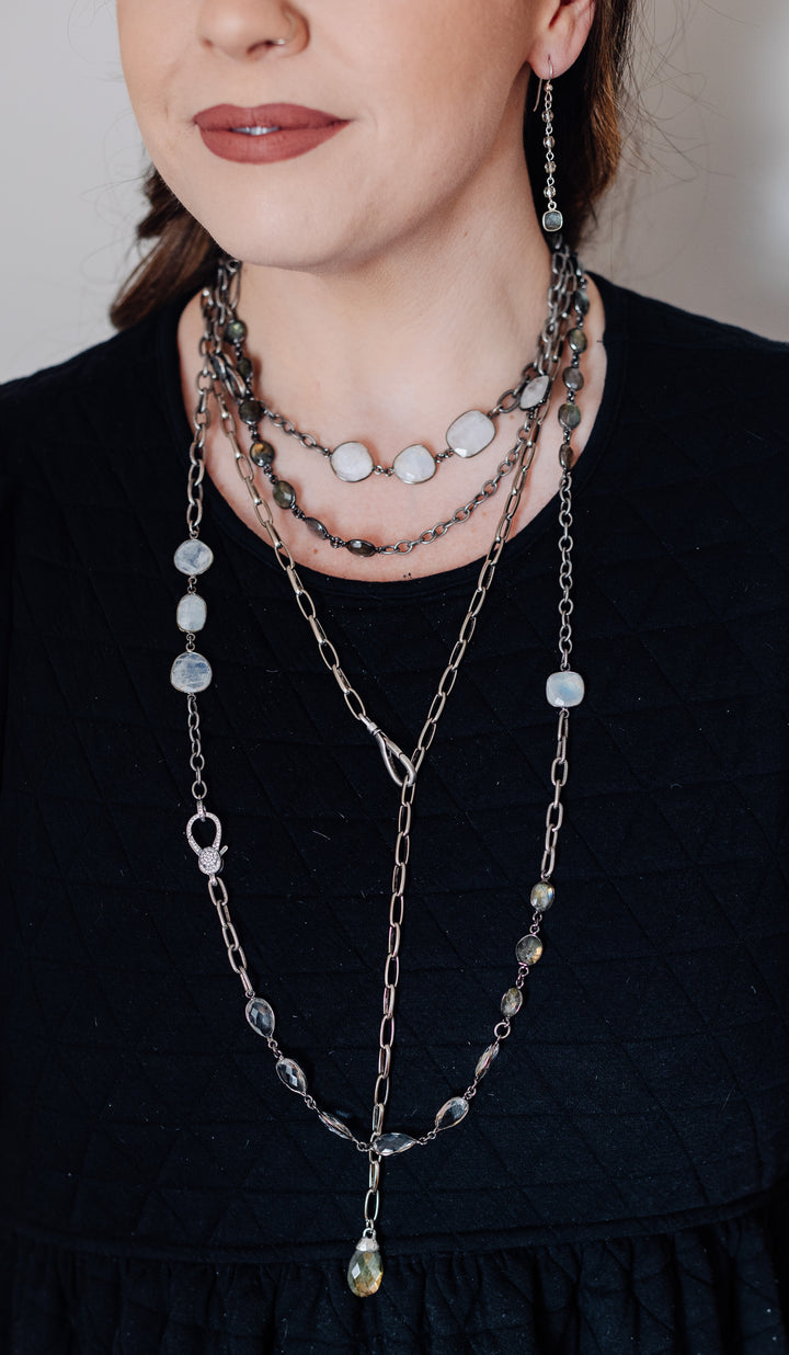 A model wearing layered chainlink and gemstone necklaces.