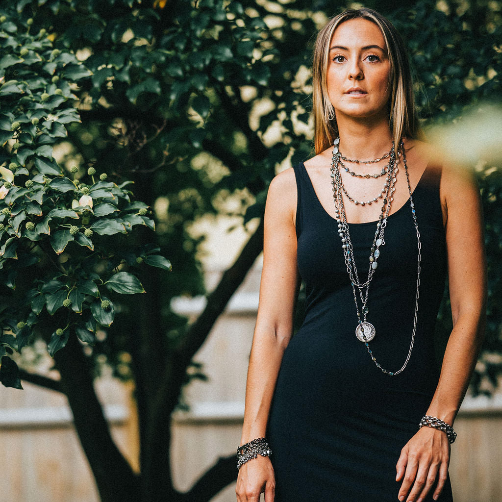 A model wearing layered chainlink and gemstone necklaces.