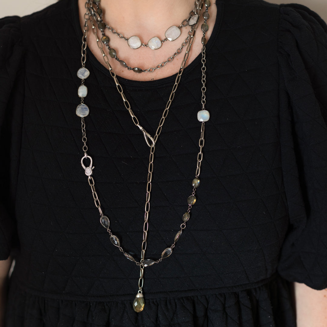 A model wearing layered chainlink and gemstone necklaces.