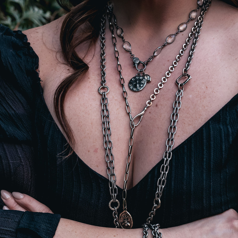 A model wearing layered chainlink necklaces.