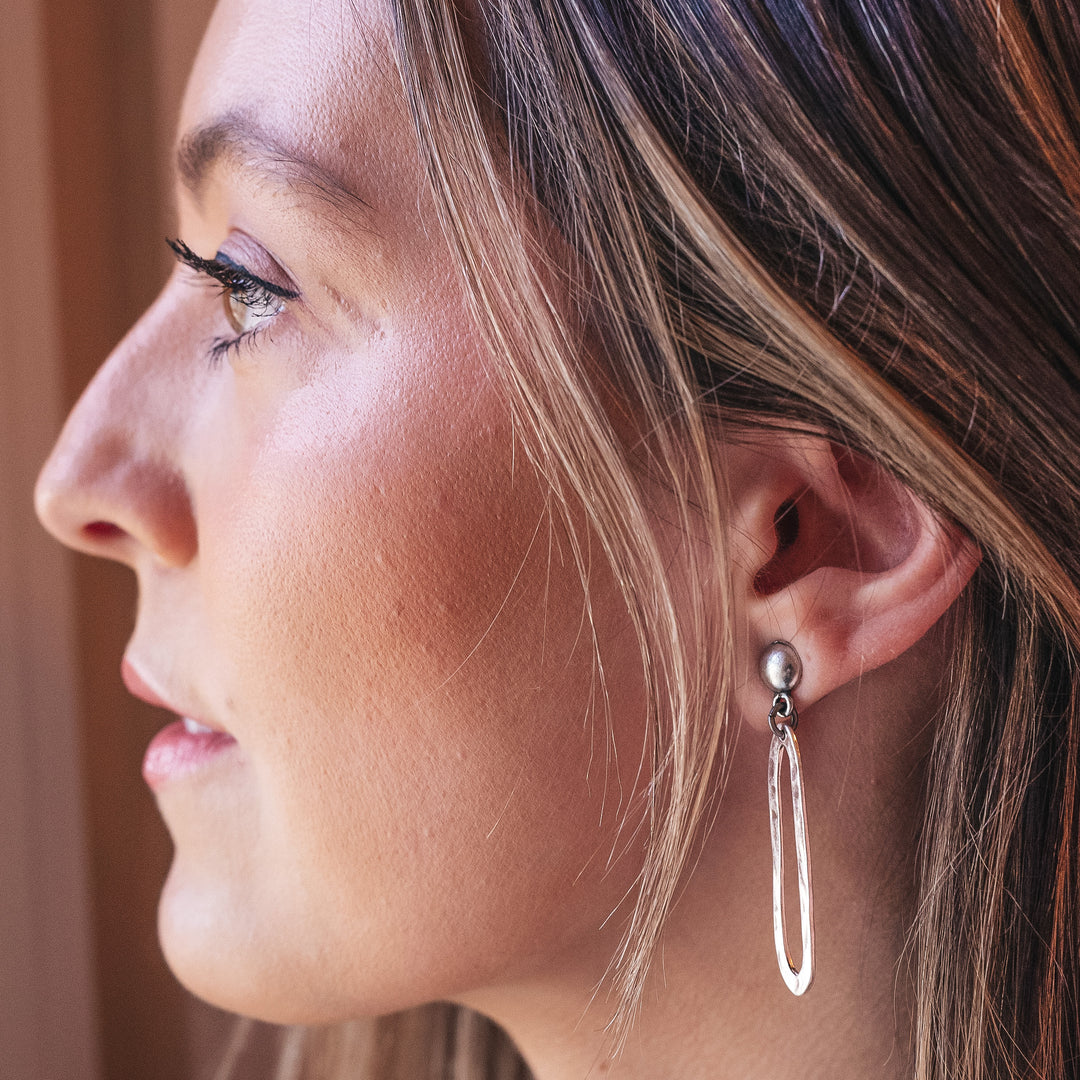 A model wearing a silver swirl drop earring.