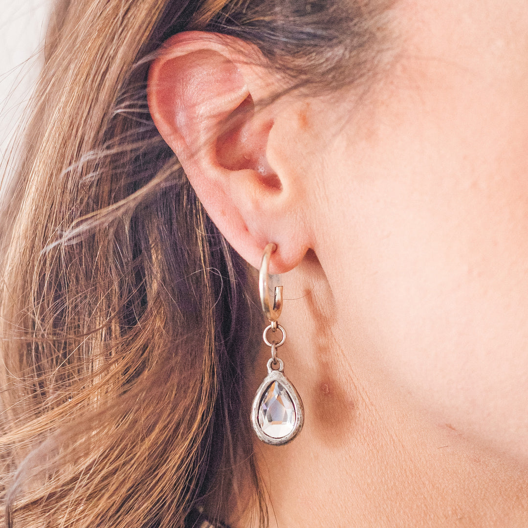 A model wearing a silver teardrop crystal earring.