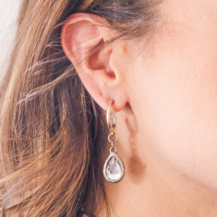 A model wearing a silver teardrop crystal earring.
