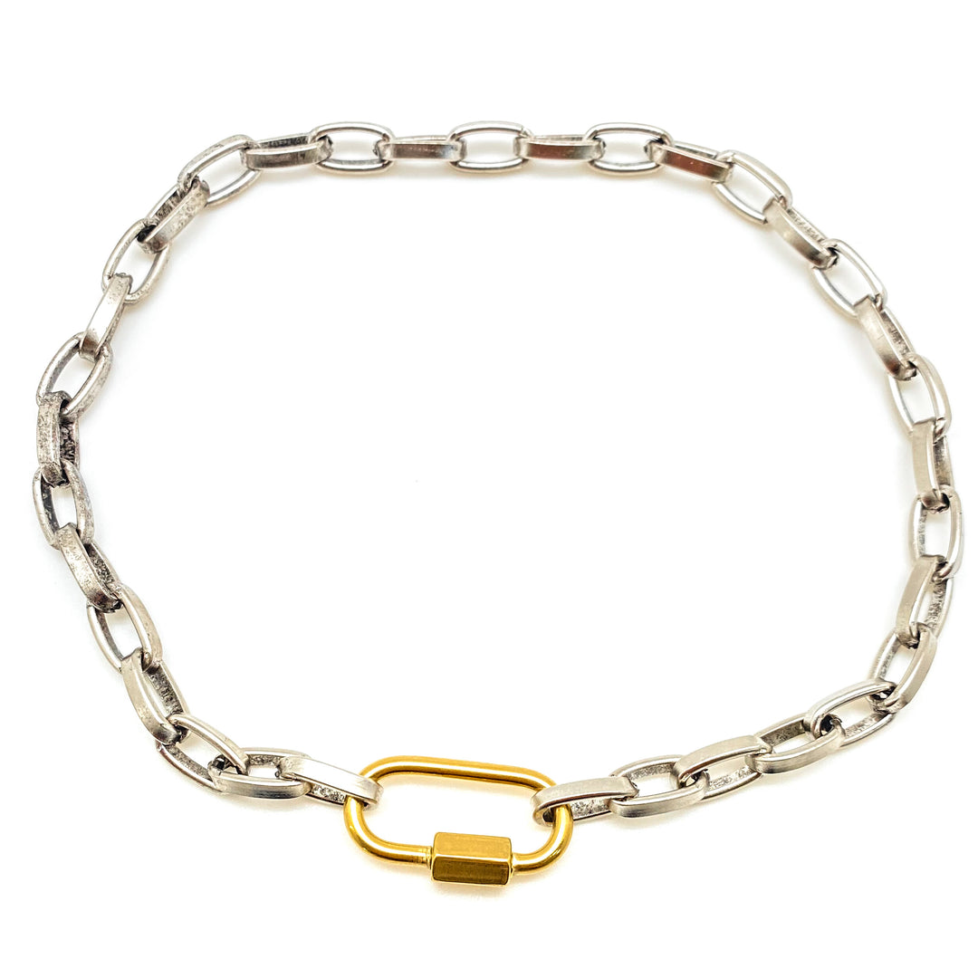 A silver paperclip chainlink necklace with matte gold carabiner link.