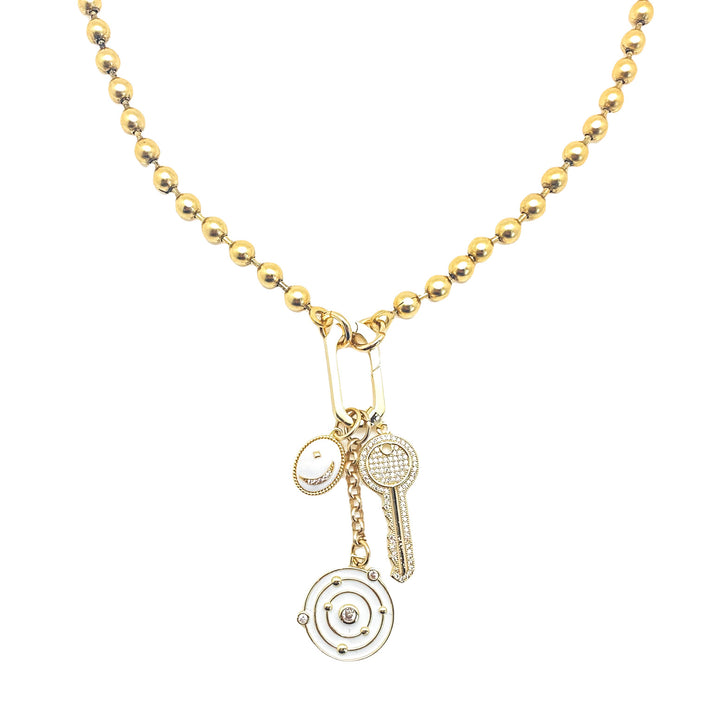 A gold ball chain necklace with white solar system, oval moon, and pave key charms.