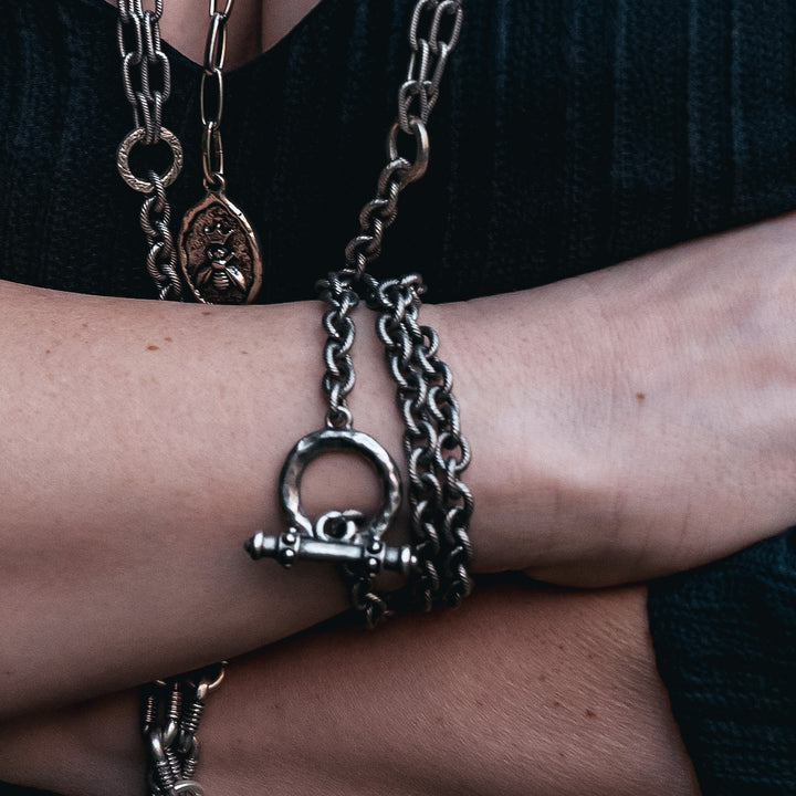 A woman modeling chainlink bracelets and necklaces.